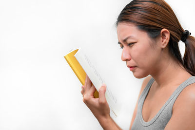 Portrait of woman reading book against white background