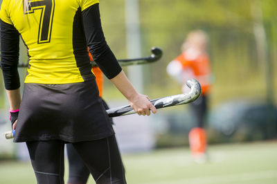 Rear view of woman holding hockey stick