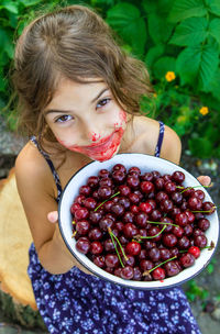 Portrait of smiling girl holding bowl of cherries