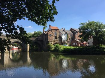 Buildings by lake against sky