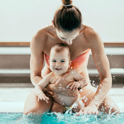 Smiling mother and son swimming in pool