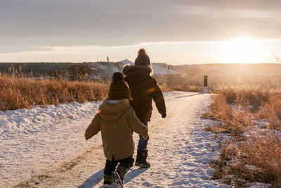Two young boys walking on snow at sunset