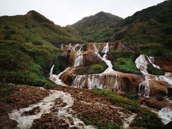 Scenic view of waterfall against sky