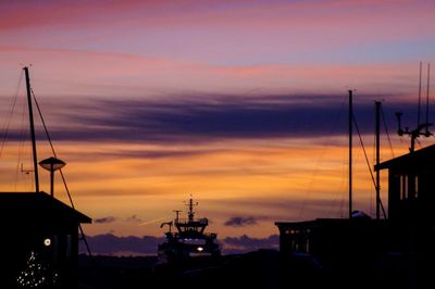 Silhouette sailboats moored at harbor against dramatic sky