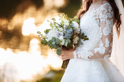 Midsection of bride holding bouquet