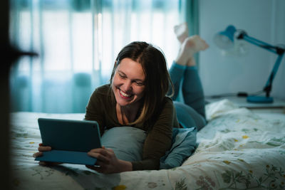 Young woman using mobile phone on bed at home