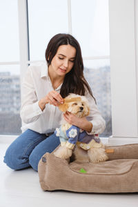 Portrait of young woman with dog sitting on sofa at home