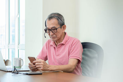 Young man using mobile phone while sitting on table