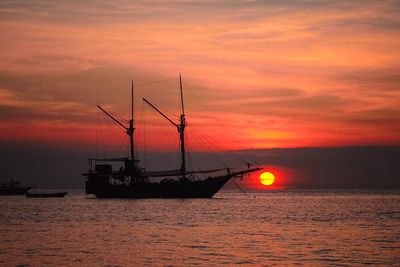Silhouette sailboat in sea against sky during sunset
