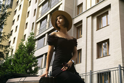 A pretty charming middle-aged woman in a black dress, hat and sunglasses strolls through the city 