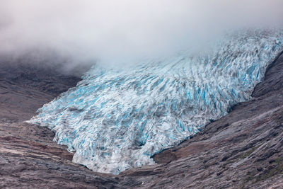 Scenic view of frozen water on mountain during foggy weather