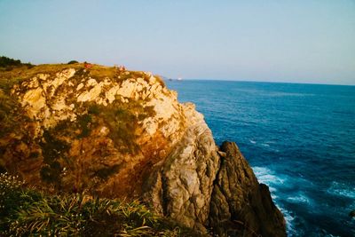 Rock formations by sea against clear sky