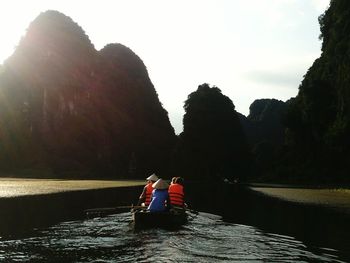 Rear view of men sitting on boat against sky