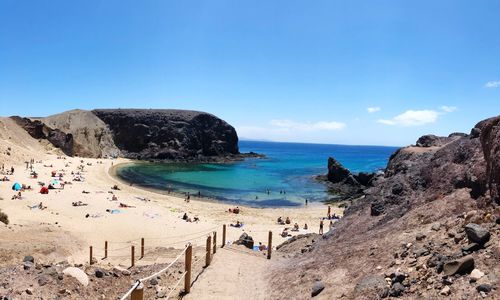 Scenic view of people at beach against sky