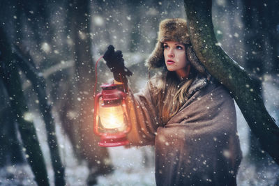 Portrait of young woman standing on snow covered road