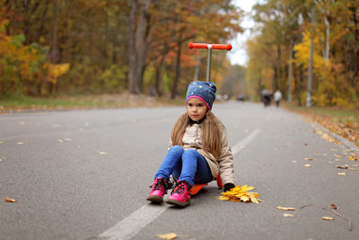 Full length of girl sitting on road