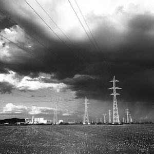 Electricity pylons on field against sky