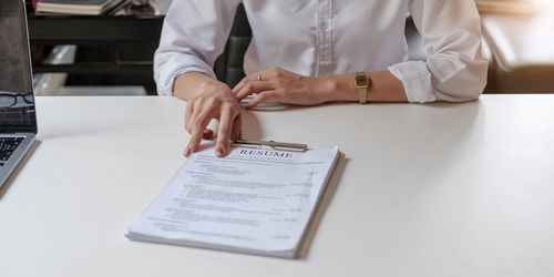 Midsection of woman with text on paper at table