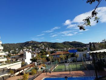 High angle view of trees and buildings against blue sky