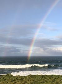 Scenic view of rainbow over sea against sky