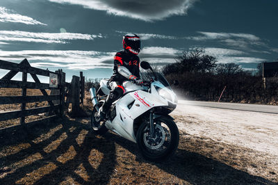 Person riding motorcycle on road against sky