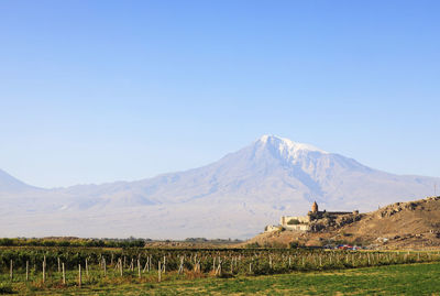 Scenic view of built structure against snowcapped mountain and sky