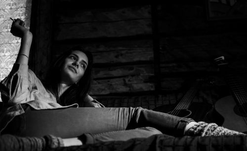 Portrait of young woman sitting on bed at home