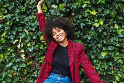 Smiling young woman standing against plants