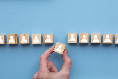 Cropped hand holding toy blocks on blue background