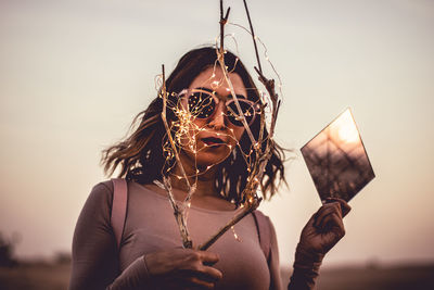 Portrait of woman holding umbrella against sky during sunset