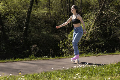 Brunette woman skating in the park with pink roller skates
