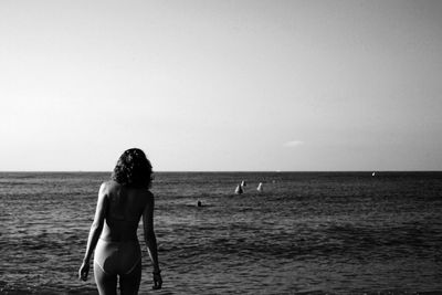 Woman standing on beach against clear sky