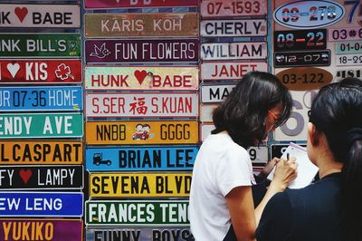 Rear view of people standing against graffiti