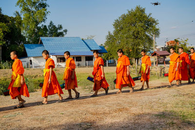 People walking by temple against sky