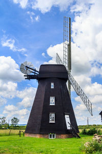 Low angle view of traditional windmill on field against sky