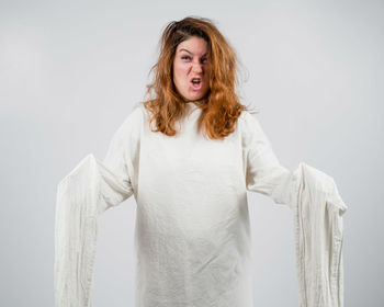 Portrait of young woman standing against white background