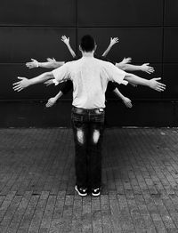 Rear view of young man standing with arms outstretched