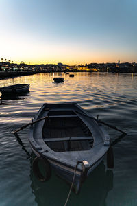 Boats moored in lake against sky during sunset