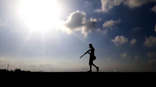 Silhouette man walking on field against sky