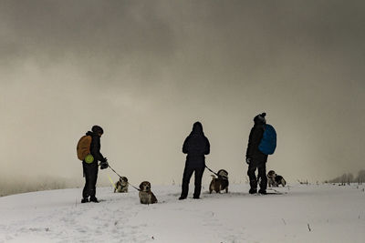 People with dog on snow against sky