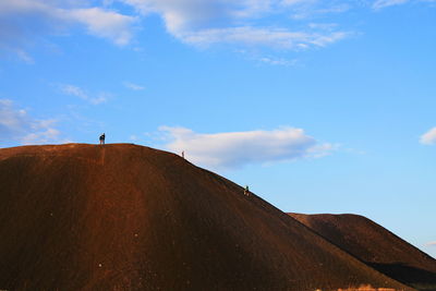 Silhouette of person standing on landscape against blue sky