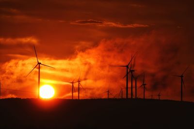 Low angle view of silhouette windmills against sky during sunset