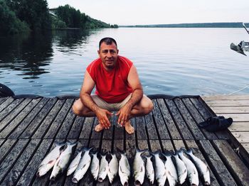 Portrait of man with fish on pier over lake