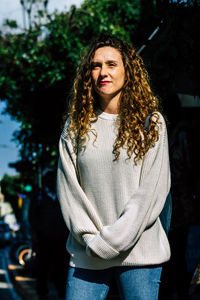 Portrait of smiling woman standing against tree