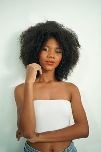 Portrait of young woman standing against white background