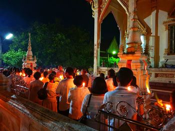 Rear view of people at illuminated temple outside building