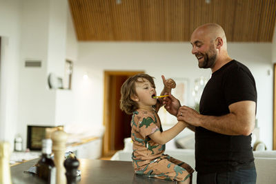 Smiling father brushing son's teeth