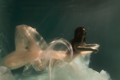 Woman with curtain swimming in pool