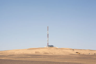 Low angle view of communications tower on land against clear sky