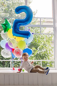 Portrait of a child boy two years old sitting on a wooden floor with balls and number two